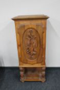 A continental oak hunting cabinet on raised legs with carved panel door