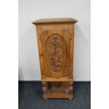 A continental oak hunting cabinet on raised legs with carved panel door