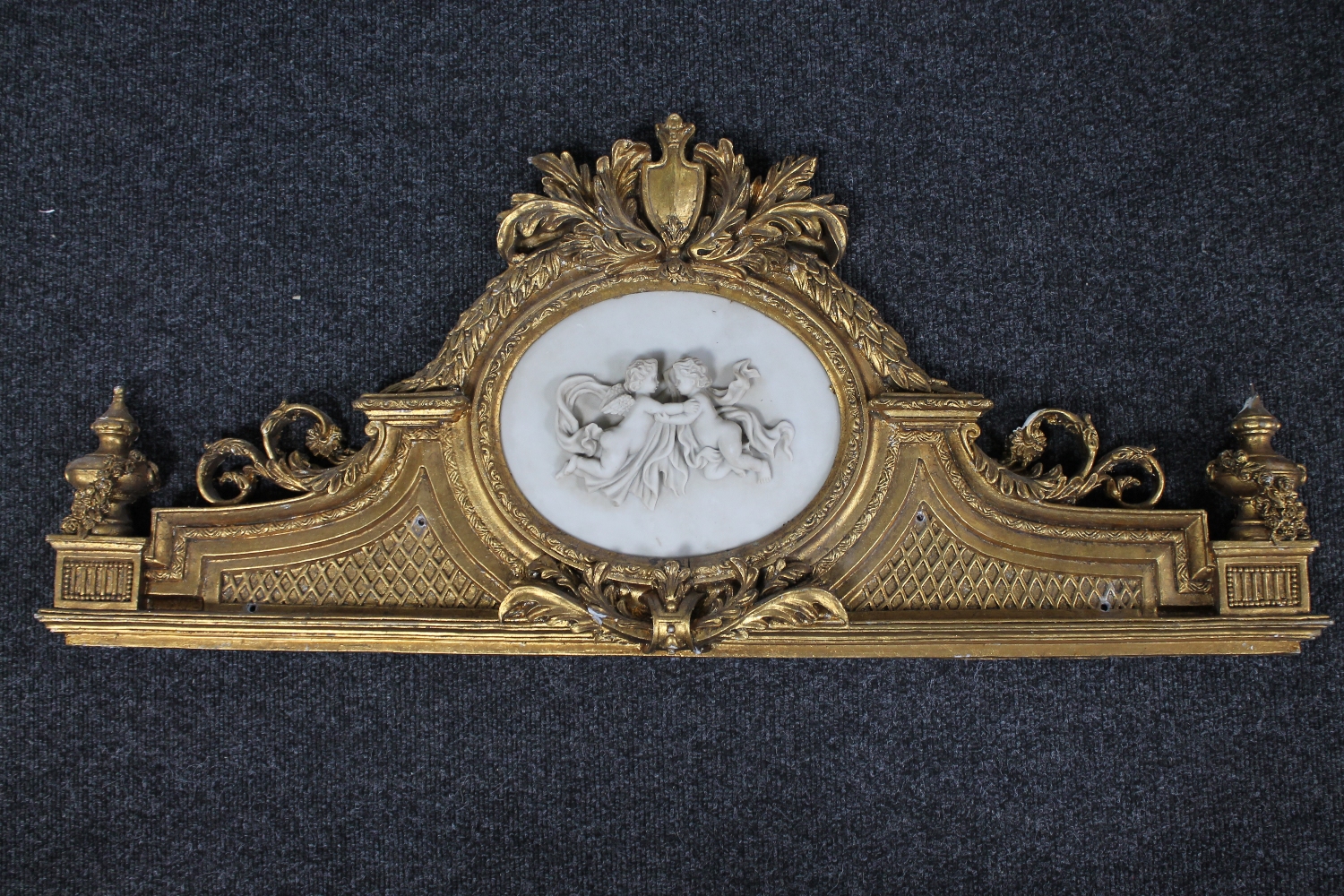A ornate gilt composite panel depicting two cherubs