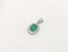 A 14ct white gold emerald and diamond pendant, featuring oval cut emerald (0.