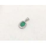 A 14ct white gold emerald and diamond pendant, featuring oval cut emerald (0.