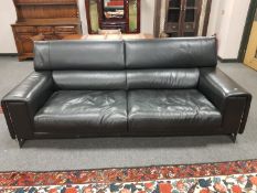 A Natuzzi black leather three seater settee on chrome support,