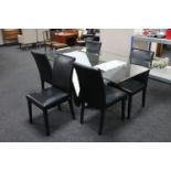A glass topped dining table and five black vinyl chairs