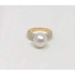 A 14ct yellow gold pearl and diamond ring featuring a cultured Akoya pearl with fifty six round