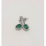 A pair of 14ct white gold emerald and diamond earrings, featuring two oval cut emeralds (1.