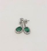 A pair of 14ct white gold emerald and diamond earrings, featuring two oval cut emeralds (1.