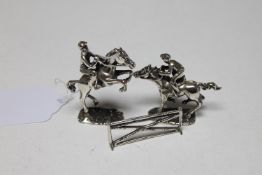 Two silver figures of jockeys on horseback together with a fence, tallest 5.