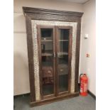 An Eastern carved hardwood glazed double door cabinet fitted with two drawers ,