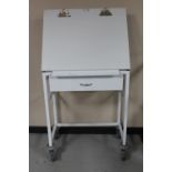 A metal medical trolley fitted a drawer with adjustable top