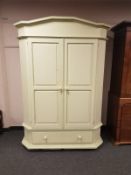 A painted double door wardrobe fitted drawer beneath,