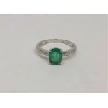 A 14ct white gold emerald and diamond ring, the emerald weighing 0.99 carat, the diamonds 0.