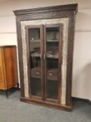 An Eastern carved hardwood glazed double door cabinet fitted with two drawers ,