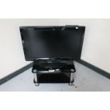 A Sharp Aquos 32" LCD TV with remote on stand