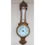 An early 20th century carved oak cased barometer with enamel dial