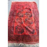 A fringed Bokhara rug on red ground