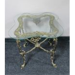 A shaped glass topped lamp table on ornate gilt metal base