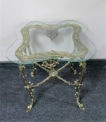 A shaped glass topped lamp table on ornate gilt metal base