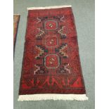 An Afghan Balouch rug on red ground 190 cm x 102 cm