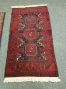 An Afghan Balouch rug on red ground 190 cm x 102 cm