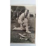 CRICKET, press photo, Doug Ring, kneeling on floor fitting pads, spectators in background, 7.75 x