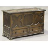 A George V oak mule chest with applied geometric mouldings, the hinged lid above two drawers, on bun