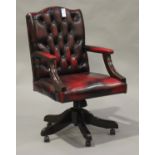 A late 20th century buttoned red leather revolving office chair, on outswept legs and castors,