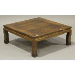 A Chinese hardwood low table, 20th century, the square panelled top raised on scroll carved legs,