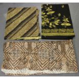 A group of mixed textiles, including a silk and lacework tablecloth, various batik printed cloth and