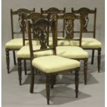 A set of six Edwardian walnut dining chairs with carved decoration, the overstuffed seats raised