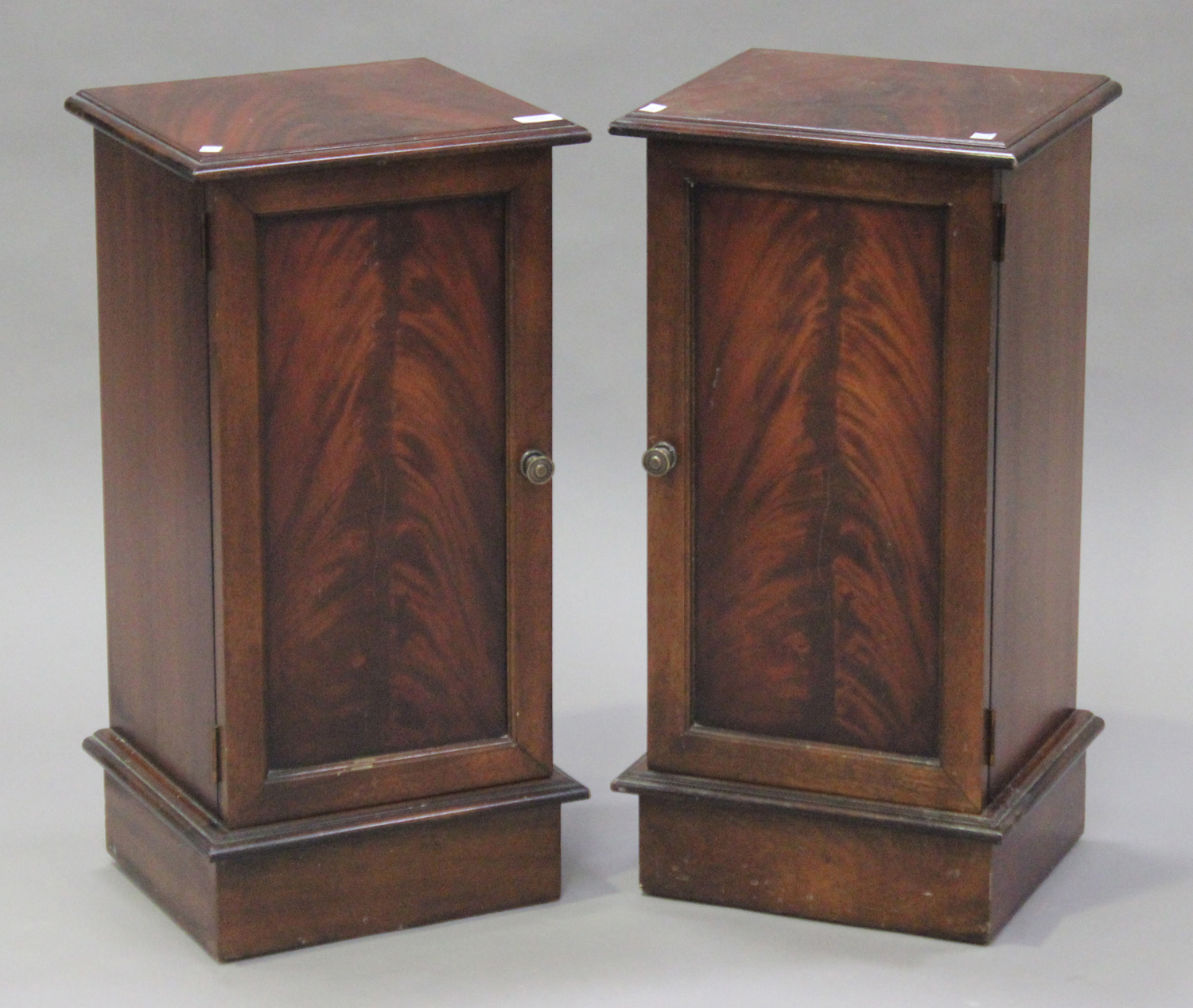 A pair of late 20th century reproduction mahogany bedside cabinets, each fitted with a panel door,