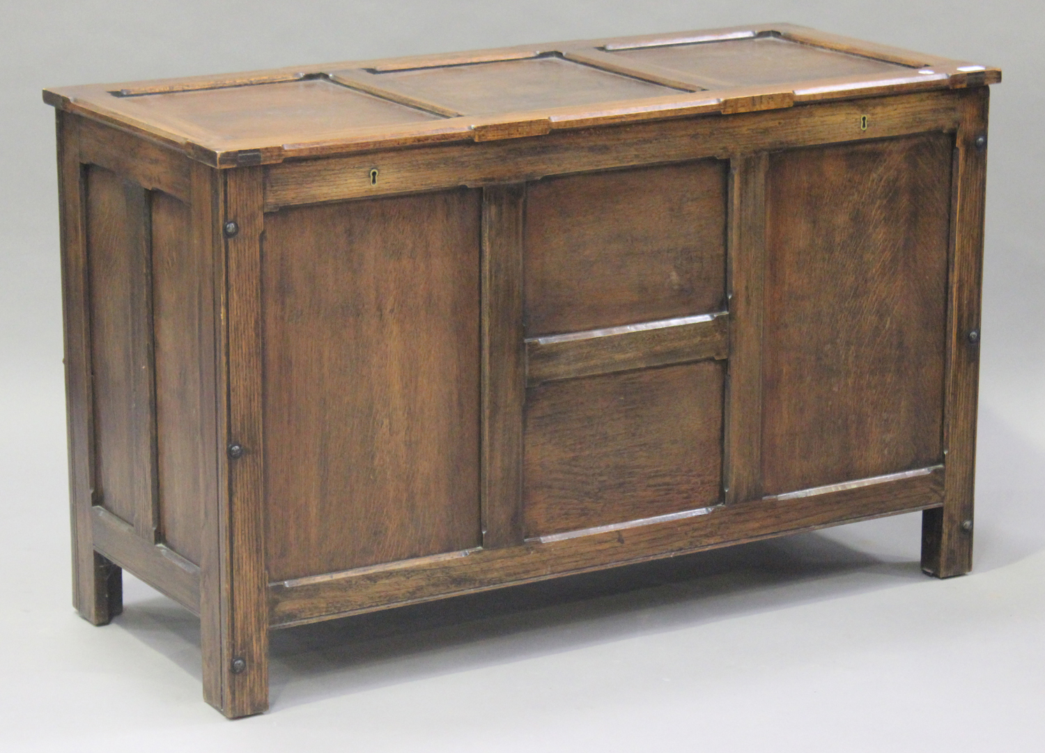 A George V oak panelled coffer, the hinged lid and panelled sides raised on stile supports, height