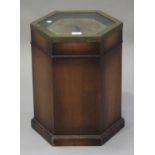 A 20th century reproduction hexagonal box table, the glazed top inset with a clock, on a plinth