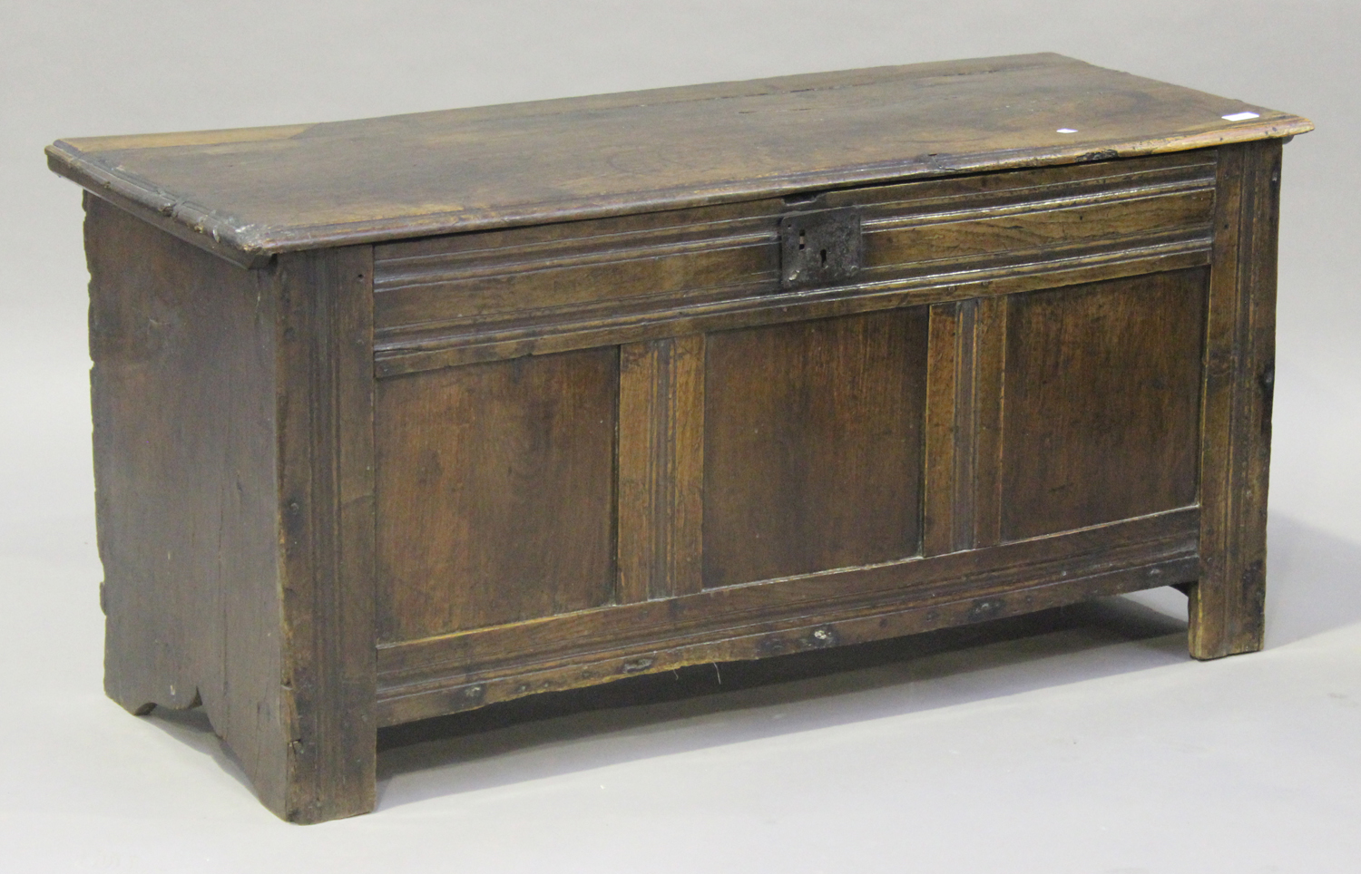 A 17th century oak panelled coffer, the hinged lid revealing a candlebox, the moulded front panels