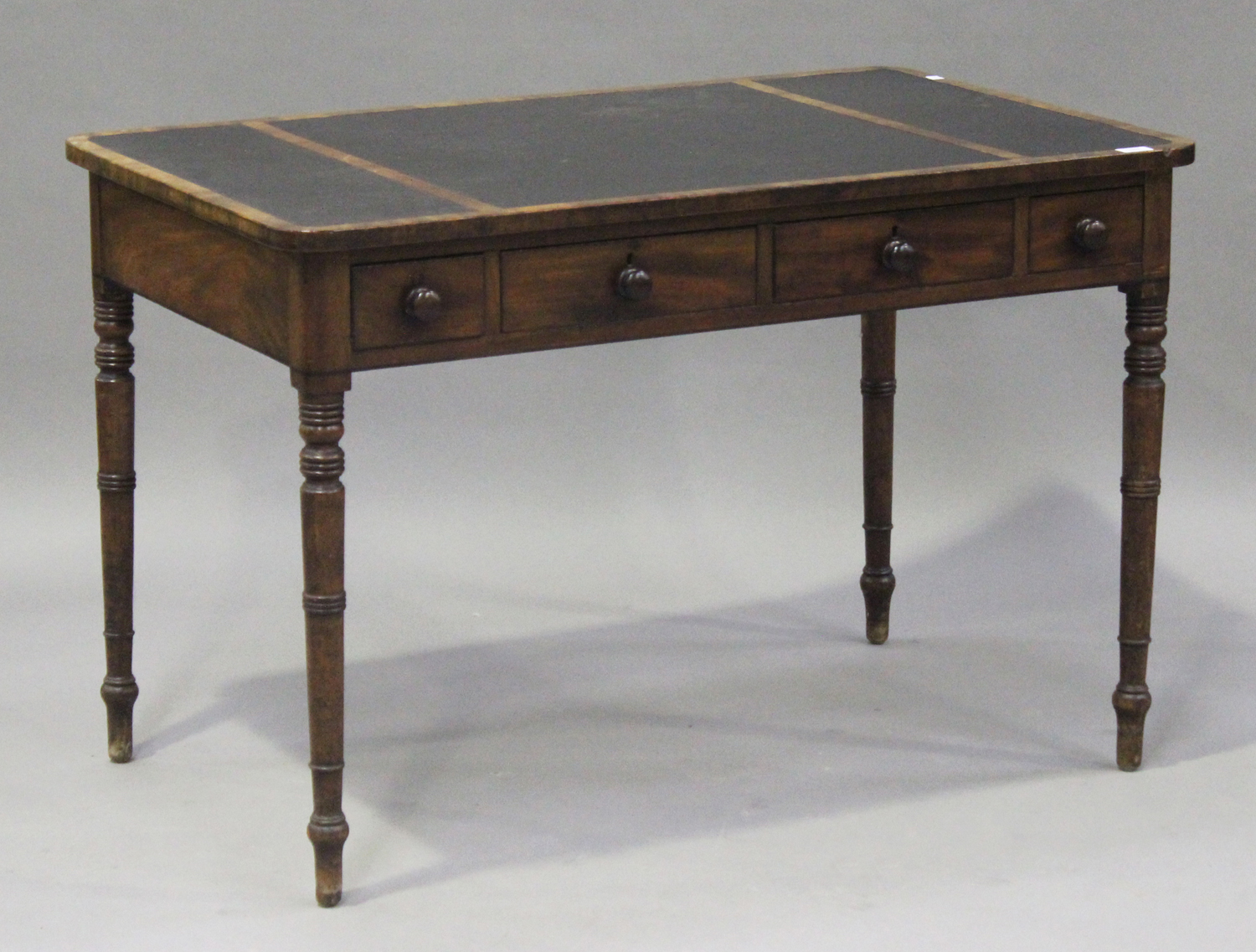 A late George III mahogany writing table with ebony banded borders, the top inset with three black