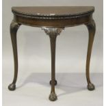 A George V mahogany demi-lune card table with carved decoration, raised on cabriole legs with claw