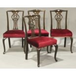 A set of four early 20th century mahogany pierced splat back dining chairs with overstuffed seats,