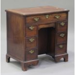 A George III mahogany kneehole desk, the moulded top above seven drawers and a cupboard, on
