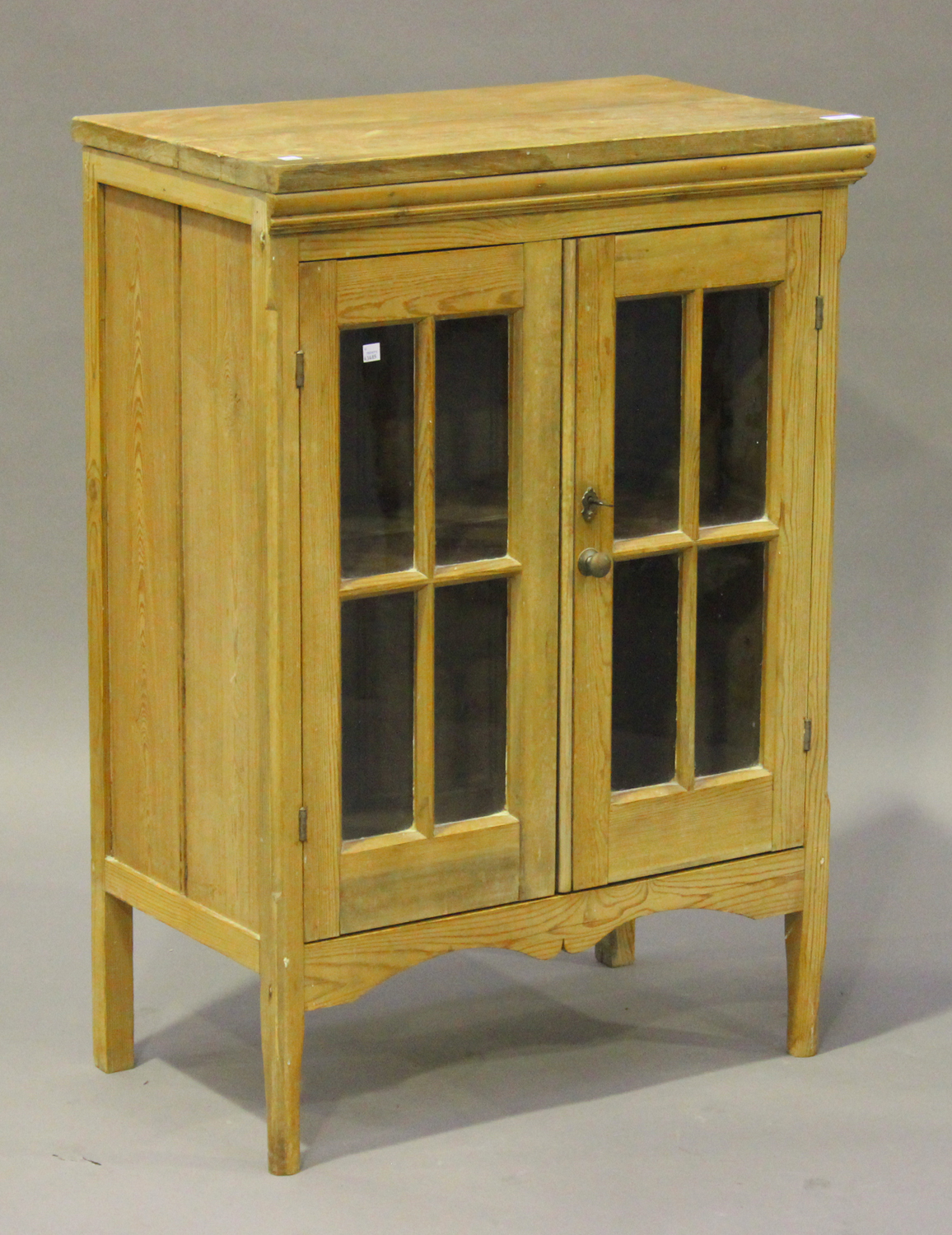 A 20th century stripped pine side cabinet, fitted with a pair of lattice glazed doors, on block