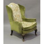 An early 20th century Queen Anne style wing back armchair, upholstered in green patterned velour,