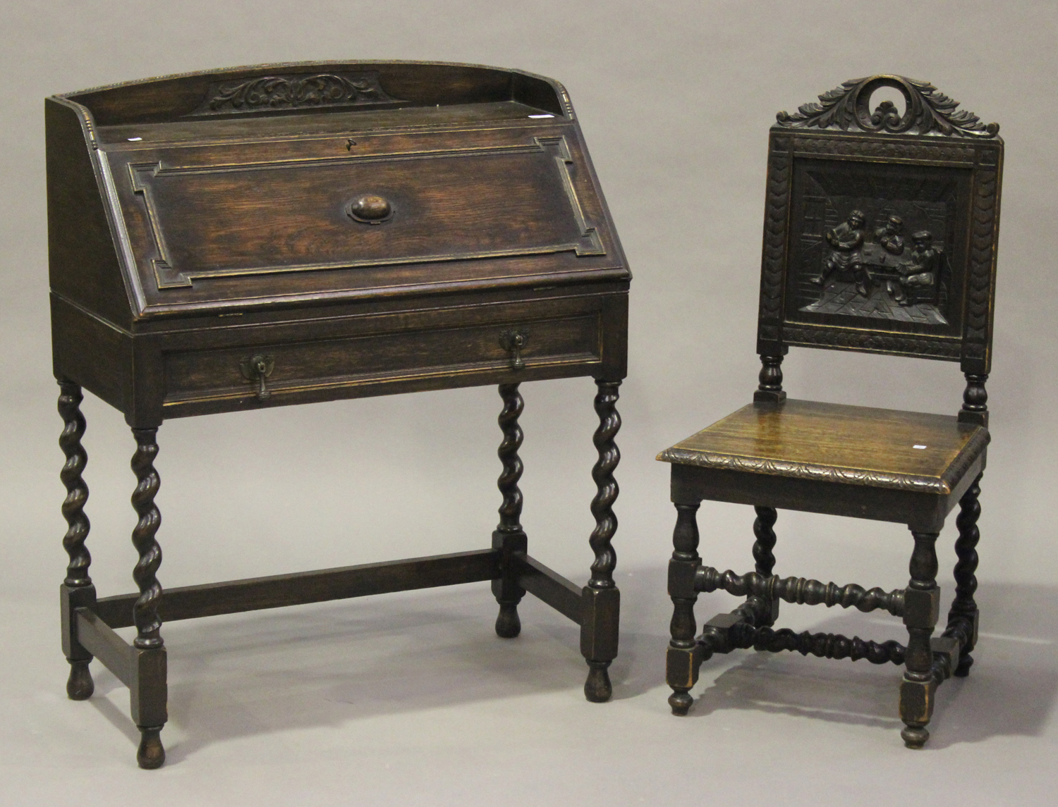 A George V oak bureau with carved decoration and applied mouldings, the fall front above a drawer,