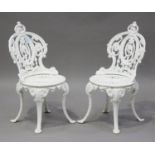 A pair of Victorian white painted cast iron garden chairs with pierced seats and backs, height 84cm,