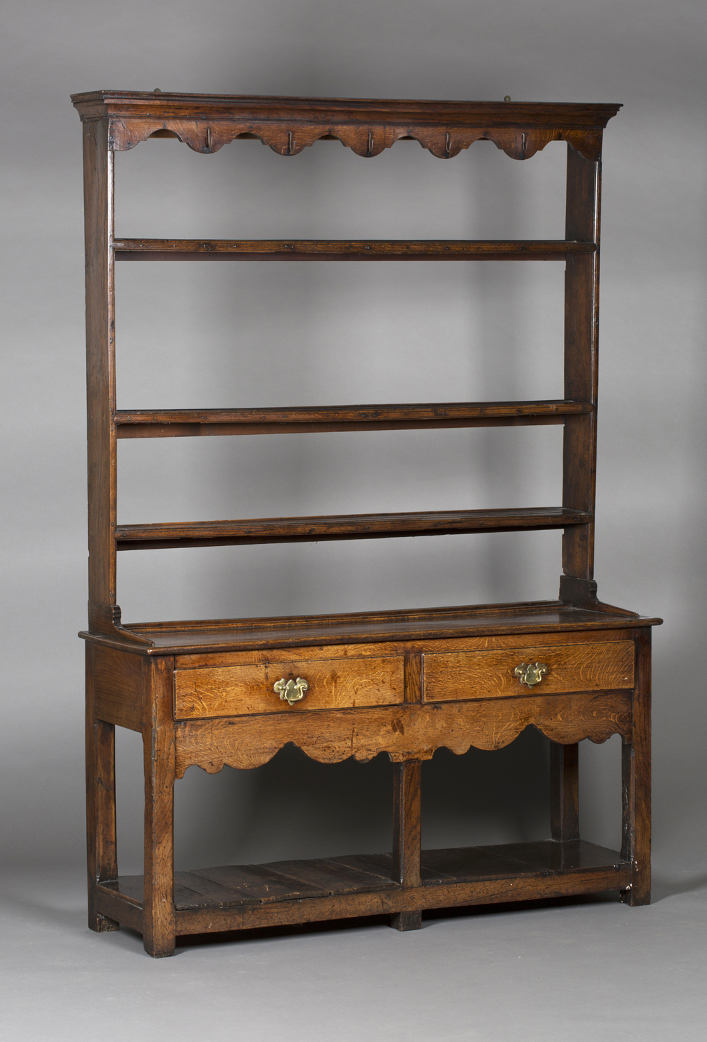 An 18th century provincial oak dresser, the shelf back with a shaped frieze fitted with wrought