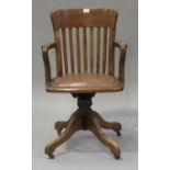 A George V oak revolving office armchair with slatted back and upholstered seat, on four outswept