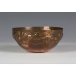 An Arts and Crafts Newlyn copper bowl, the circular hammered body decorated in relief with a band of