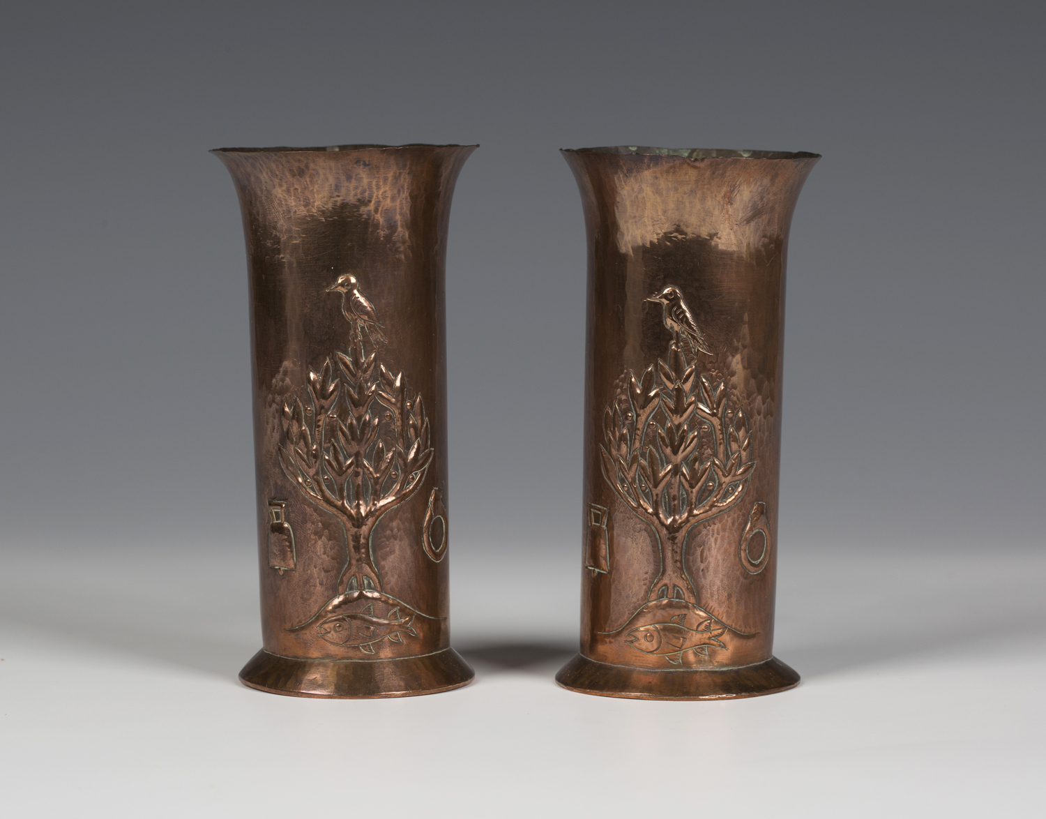 A pair of Keswick School of Industrial Arts hammered copper cylindrical vases, each worked with