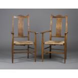 A pair of Edwardian Arts and Crafts oak elbow chairs, in the manner of C.F.A. Voysey, the splat