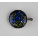 An Arts and Crafts silver mounted enamelled circular brooch by Ernestine Mills, in a blue and