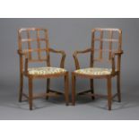 A pair of early 20th century Heal & Son style oak framed elbow chairs, the lattice backs and