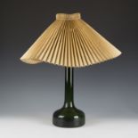 A mid-20th century Danish green glass table lamp with gilt metal collar and paper shade, height