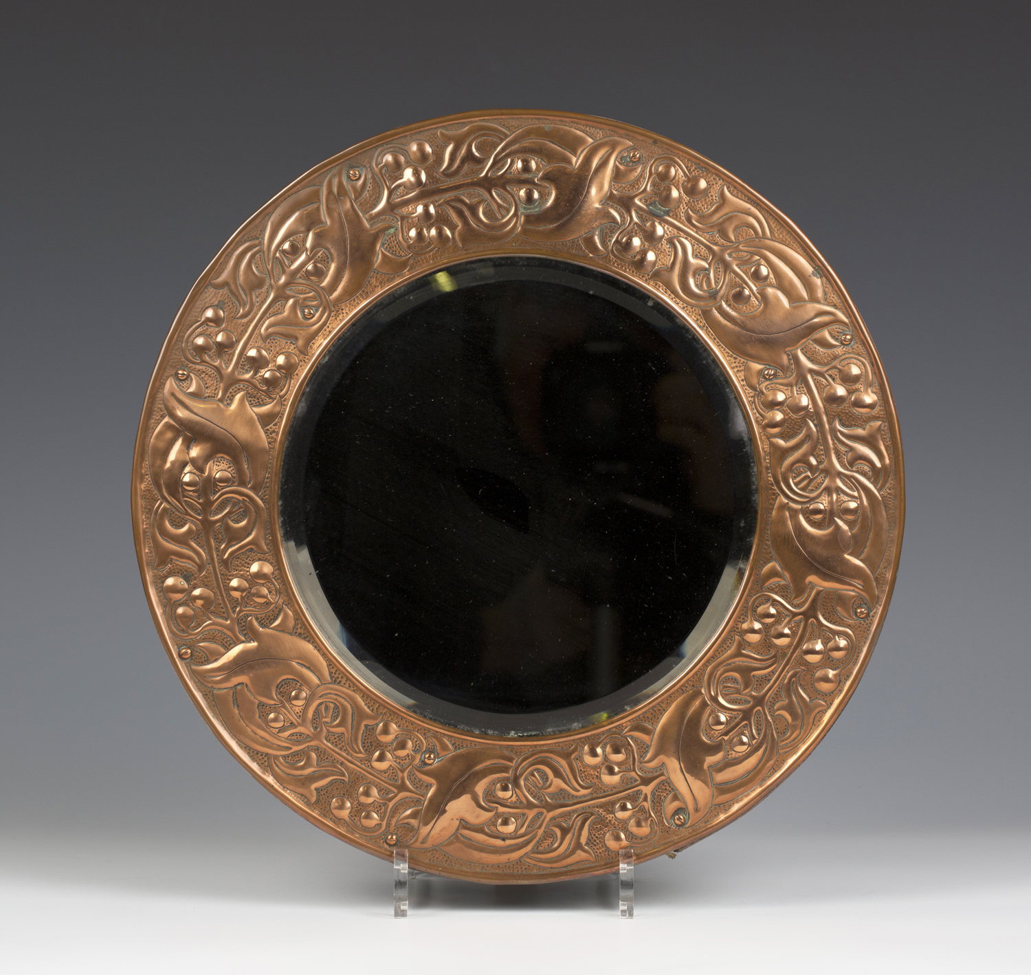 An Arts and Crafts copper mounted circular wall mirror, the bevelled plate within a wide frame